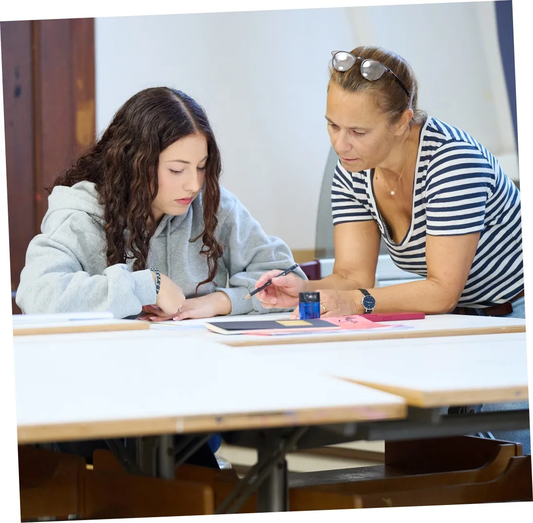 Eine Lehrerin unterstützt eine Schülerin bei einer Aufgabe